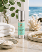 Frolana Natural Restorative Eye Cream for mature skin, displayed on a marble surface in a spa-like coastal setting with folded white towels, a bowl of cream, coral decor, and an ocean view.